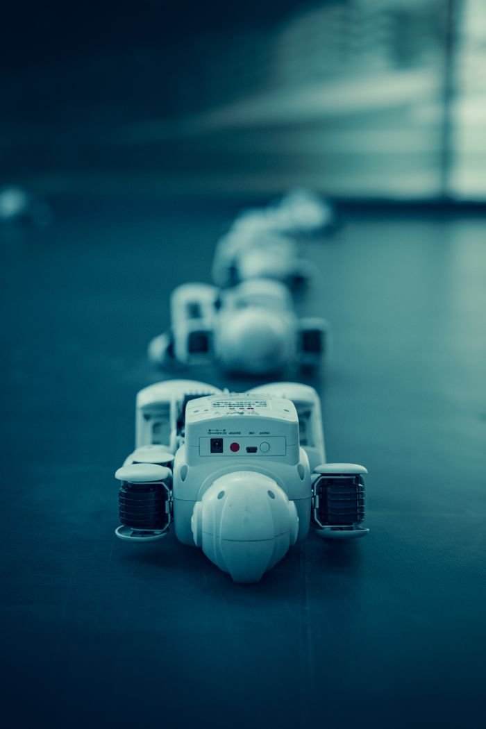 Contact Vertical shot of white robots aligned on a dark surface, emphasizing technology.