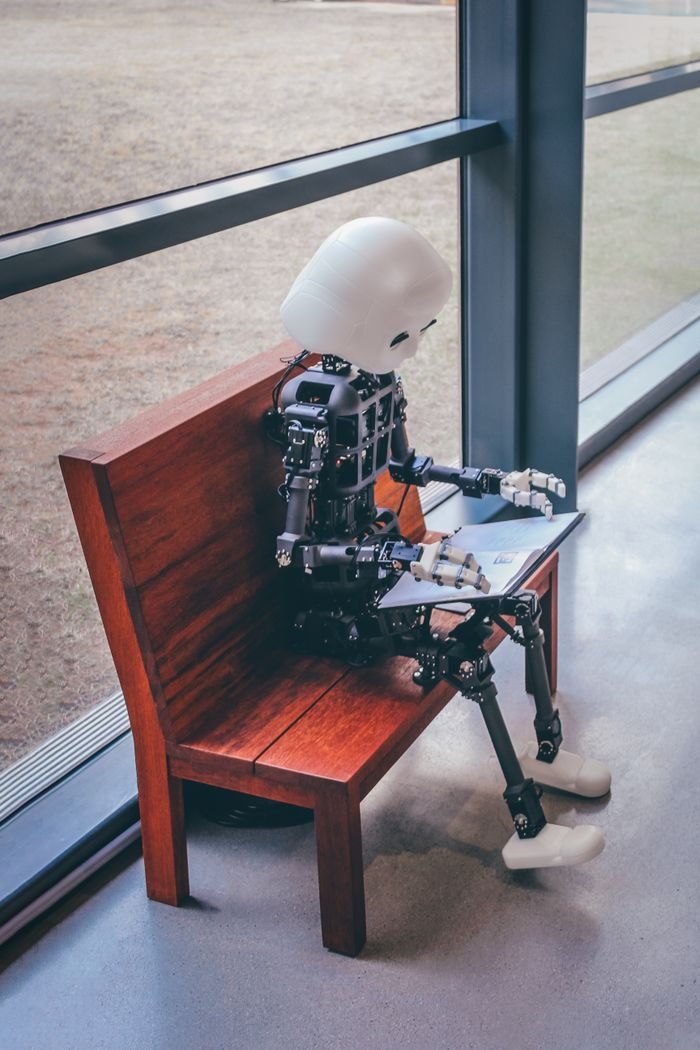 Services A humanoid robot sits on a wooden bench, reading in a modern setting in Seoul.