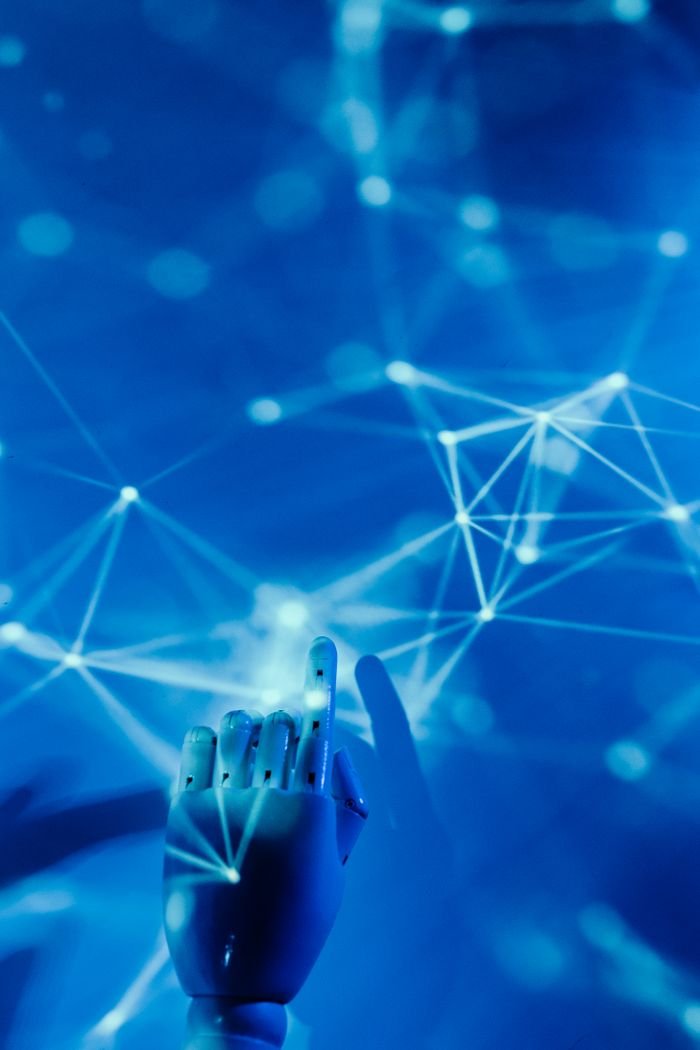 About Futuristic robotic hand touching a digital network on a blue background.